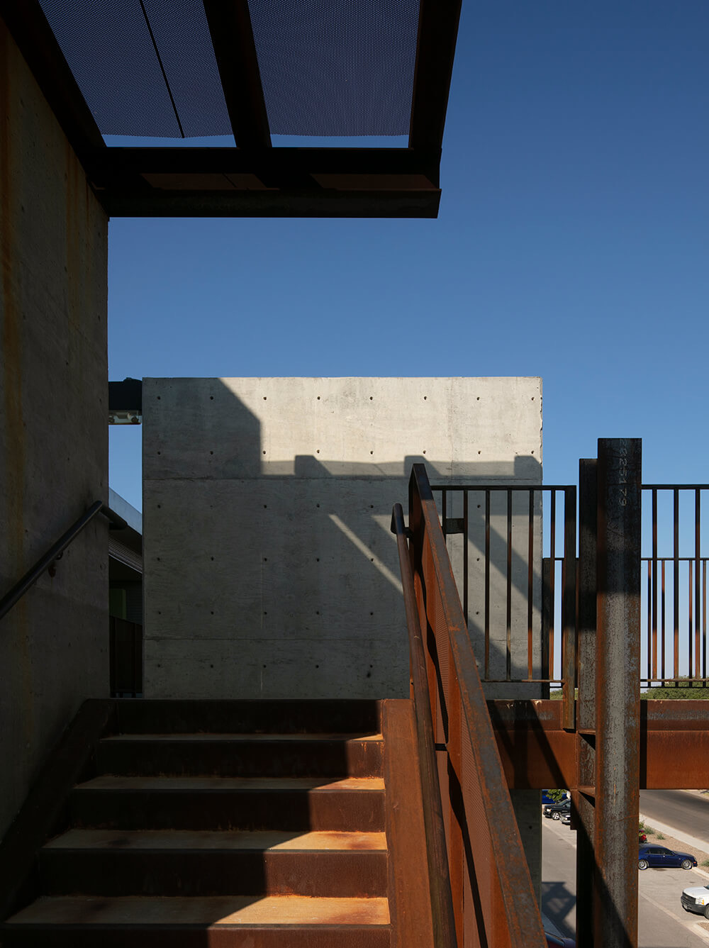 Weathered-steel stair and shade canopy against a deep blue sky at Playa Escondida