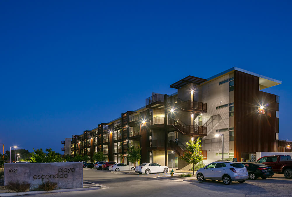 The four-story buildings and entrance sign of Playa Escondida at dusk in Hobbs, NM